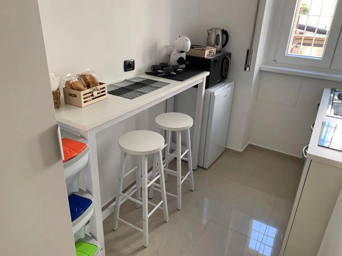 A Casa di Elisa — La cucina con il bancone, gli sgabelli bianchi, il bollitore e il microonde